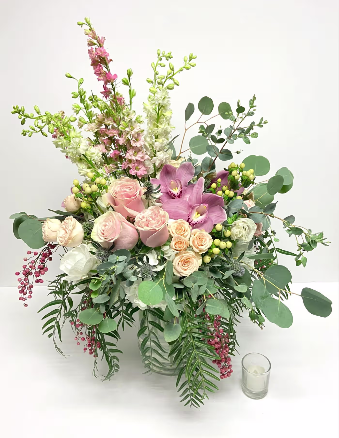 Hand-designed arrangement with pink roses, cymbidium orchids, snapdragons, and eucalyptus in a glass vase