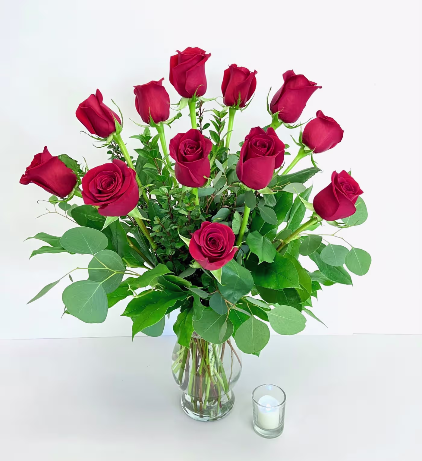 Red rose bouquet in glass vase with greenery, ideal for Engagement Parties