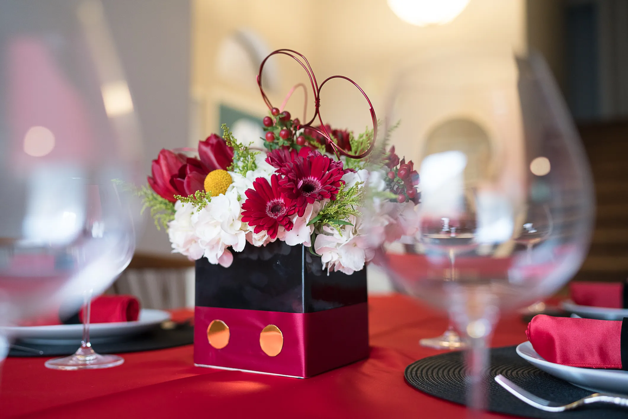 Baby-Shower-2 (1) Baby shower and gender reveals centerpiece with red gerbera, tulips, white hydrangea, and hypericum berries in a black and red themed box vase on a red linen table