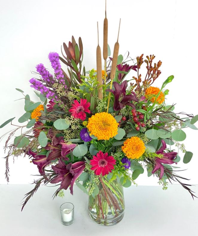 Custom fall flower arrangements featuring marigolds, gerbera daisies, and cattails for autumn decor