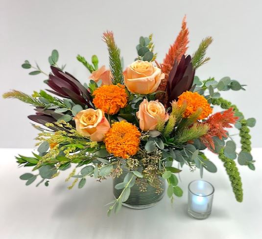 Orange rose and marigold Thanksgiving flowers and centerpieces in Phoenix with eucalyptus and a candle accent